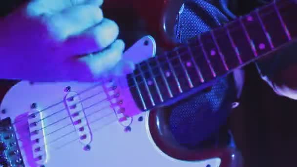 Mężczyzna ręce w neon światło grać na gitarze elektrycznej na koncert — Wideo stockowe