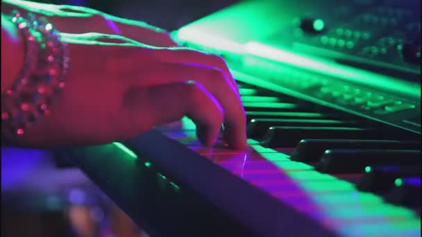 Decorated hands play synthesizer keys in neon light — Stock Video