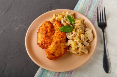 Bej salata tabağında fırında tavuk göğsü ve çatalın yanında ananas..