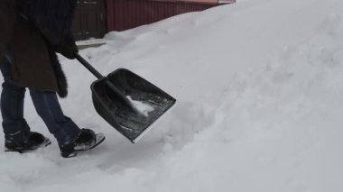 Kürekli bir kadın, kar yağdıktan sonra karları temizler.