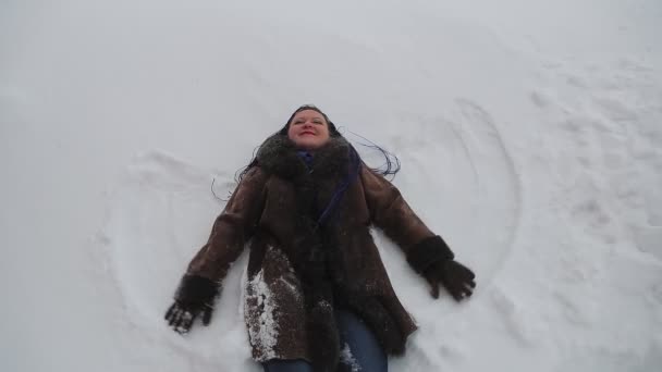 Une femme dans un manteau chaud avec des tresses afro se trouve dans la neige dans la neige et se réjouit dans les sourires d'hiver — Video