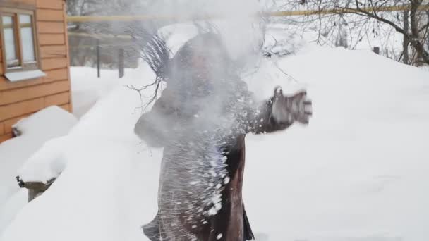 A happy woman in a warm coat with afro braids throws snow — Stock Video