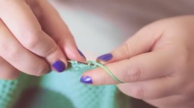 Kadınların elleri basit bir desenle örgü iğnelerini ve yün örgülerini tutarlar.