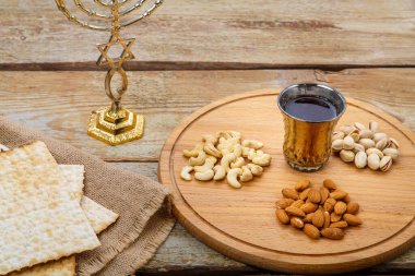 Çuvallama üzerine Matzah, fındıklı yuvarlak bir tahta, ahşap bir masa ve bir menorah üzerine bir bardak şarap. Yatay fotoğraf