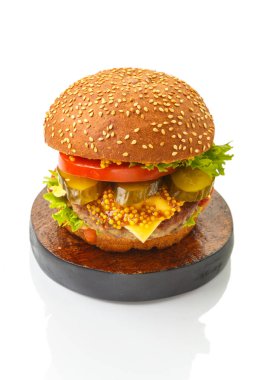 Biftekli klasik burger, soslu peynirli sebzeler kahverengi yuvarlak bir tabakta susam tohumlu ekmek. Dikey fotoğraf