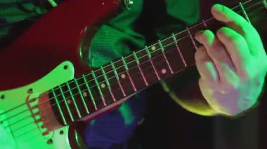 Bir konserde neon lambalı erkek eller elektro gitar çalar. Ortam planı