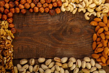 Ahşap bir masada çeşitli fındıklar çerçevesi. Boşluğu kopyala.