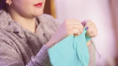 Bir kadın yün bir yelek örüyor..