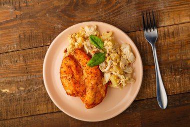 Fırında tavuk göğsü ve salata. Tabakta salata, ahşap bir masanın çatalının yanında..