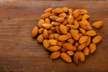 Badem fındıkları koyu ahşap bir masaya serpiştirilir..