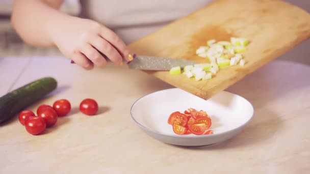 Жіноча рука ножем кидає нарізане яблуко в тарілку з салатом — стокове відео