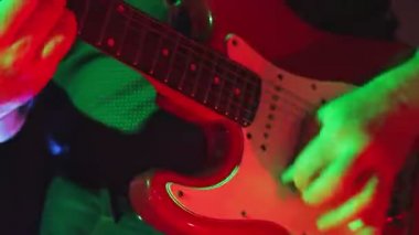 Neon lambalı erkek eller sağ elinde konser gitarıyla elektro gitar çalar.