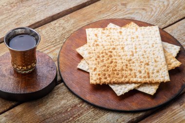 Tahta bir masada matzah ve yuvarlak bir tahtanın üzerinde bir bardak şarap..