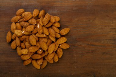 Badem fındıkları koyu ahşap bir masaya serpiştirilir..