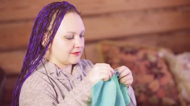 Mavi afro saçlı, yün kazak ören bir kadın.