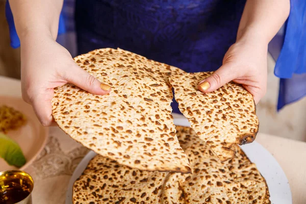 Hamursuz Bayramı masasındaki Yahudi bir kadın shmura matzah 'ı kırıyor..