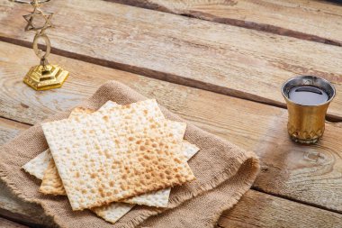 Tahta bir masada matzah ve bir bardak şarap. Masadaki menoranın yanında çocuk için..