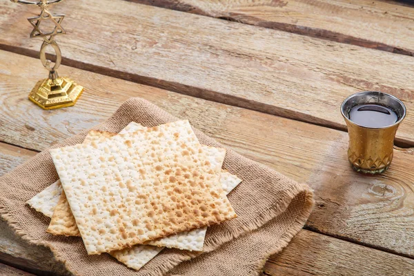 Tahta bir masada matzah ve bir bardak şarap. Masadaki menoranın yanında çocuk için..