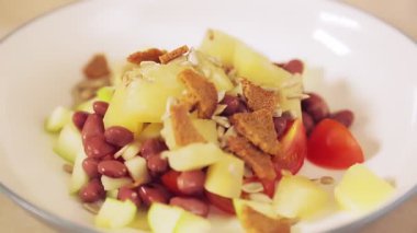 Bir kadının eli ananaslı salataya kızarmış ekmek serper.