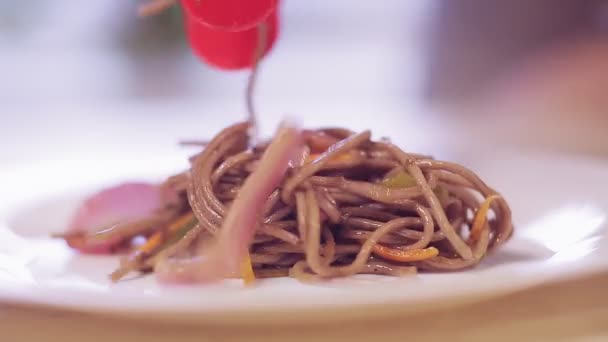 Nippers přesunout soba s houbami a zeleninou z pánve na talíř — Stock video