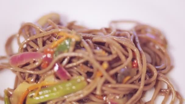 Nippers transferir o soba com cogumelos e legumes da panela para uma placa — Vídeo de Stock