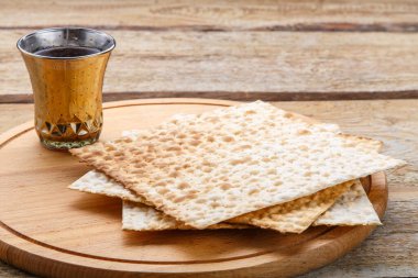 Yuvarlak ahşap bir tahta matza ve bir bardak kiraz şarabı üzerinde.