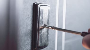 Kadın el anahtarı tutar ve deliğe sokarak giriş kapısını açar.