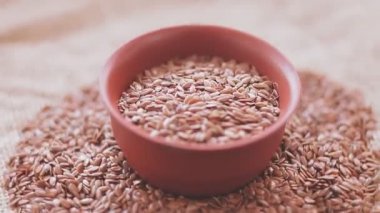 Kahverengi keten tohumlu bir kase bir çuval üzerinde durur ve bir daire içinde döner.