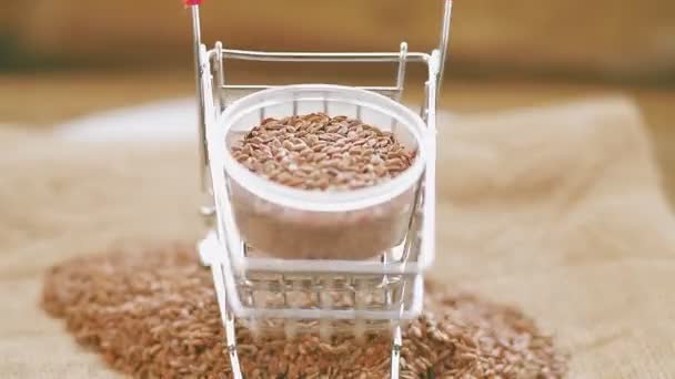 Un carro de comida con semillas de lino marrón cabalga sobre el suelo de madera — Vídeos de Stock
