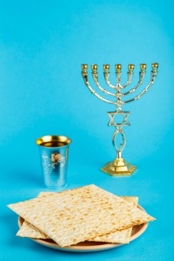 Mavi arka planda Magen Dovid 'in hazırladığı Matzo tabakları ve Kiddush ve Menorah için bir bardak şarap..