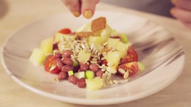 Bir kadının eli ananaslı salataya kızarmış ekmek serper.