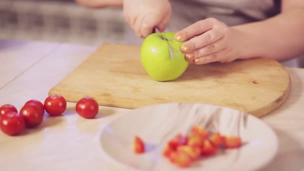 Een vrouwenhand snijdt een groene appel op een houten plank. — Stockvideo