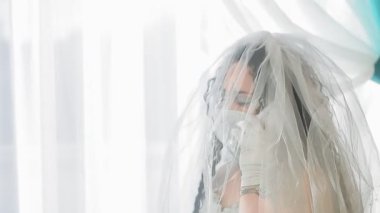 Gelinlik ve duvak takmış Yahudi bir gelin. Sinagogda tıbbi maske takıyor. Chupah töreninden önce telefonda konuşuyor.