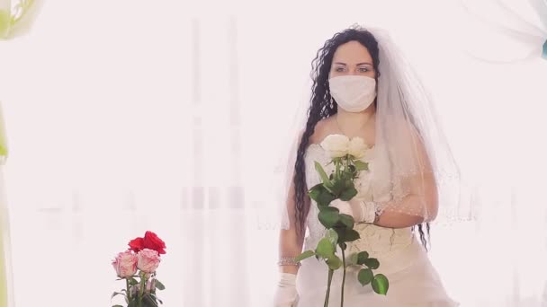 Una sposa ebrea con un abito da sposa e un velo con una maschera medica si gira verso la telecamera e cerca qualcuno — Video Stock