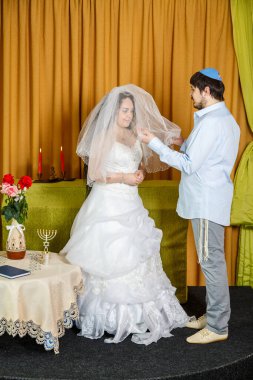Sinagog düğününde yapılan chuppah töreninde damat gelini Badeken seremonisinde peçeyle örtüyor..