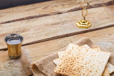 Tahta bir masada matzah ve bir bardak şarap. Masadaki menoranın yanında çocuk için..