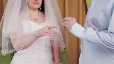 Bir sinagogdaki Yahudi gelin ve damat, chuppah töreni sırasında, damat, yüzsüz bir fotoğraf için gelin işaret parmağına bir yüzük takar.