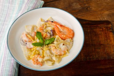 Kremalı soslu makarna. Gri bir tabakta. Peçetedeki ahşap masada. Yatay fotoğraf