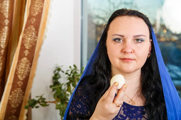 Еврейская Женщина Головой Покрытой Голубым Плащом Пасхальным Столом Съедает Яйцо — стоковое фото