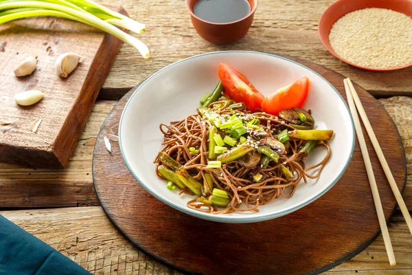 Mantarlı soba, yeşil fasülye ve susam tohumları soya sosu ve soya sosunun yanındaki tahta masada bir tabakta. Yatay fotoğraf