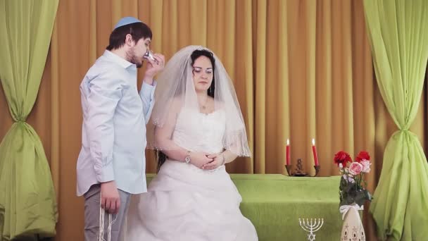 During the chuppah ceremony, the Jewish bride and groom in the synagogue drinks wine. — Stock Video