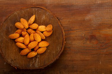 Badem fındıkları ahşap bir masada yuvarlak bir tahtaya saçılmış..