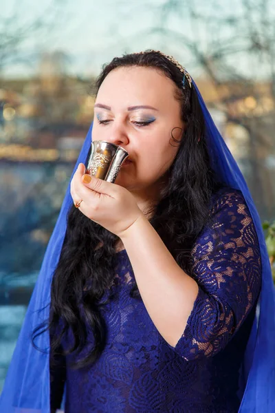 在逾越节餐桌上，一位头戴蓝色斗篷的犹太妇女喝着基杜什葡萄酒. — 图库照片