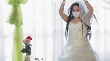 Gelinlik ve duvak takan bir Yahudi gelin düğün töreninden önce başını duvakla örtüyor. Ortam planı