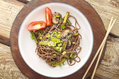 Mantarlı soba ve yemek çubuklarının yanındaki tahta masada bir tabakta susam tohumu. Yatay fotoğraf.