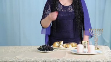 Yüzü olmayan Yahudi bir kadın Şabat yemeğinde masada üzüm yer. Ortam planı