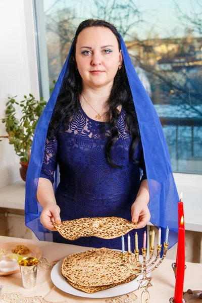 在逾越节的种子桌上 一个黑发犹太女人 头戴蓝色斗篷 打破了玛佐的头巾 垂直照片 — 图库照片