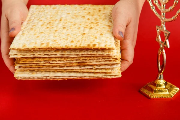 Een Stapel Matzo Vrouwelijke Handen Een Rode Achtergrond Bij Menorah — Stockfoto