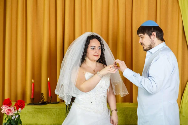 During a chuppah ceremony at a Jewish synagogue wedding, the groom puts a ring on the brides index finger. — Stock Photo, Image