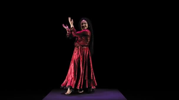 A barefoot gypsy woman with long hair in a red suit dances beautifully on a black background — Stock Video